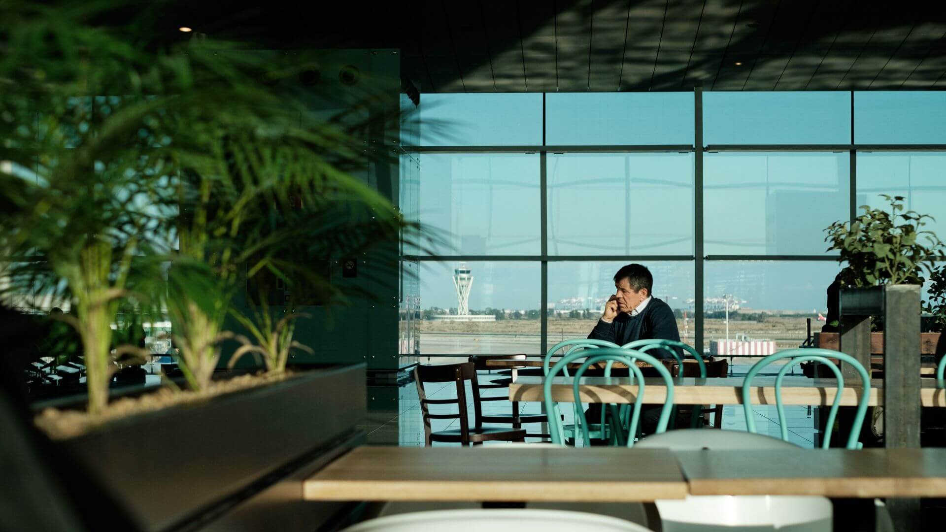 man-call-phone-airport-cafe-restaurant-plants-table-chair