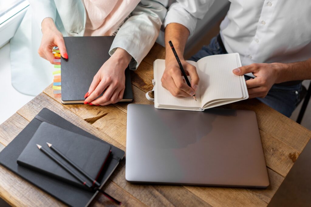 Two people sitting at the desk making notes
