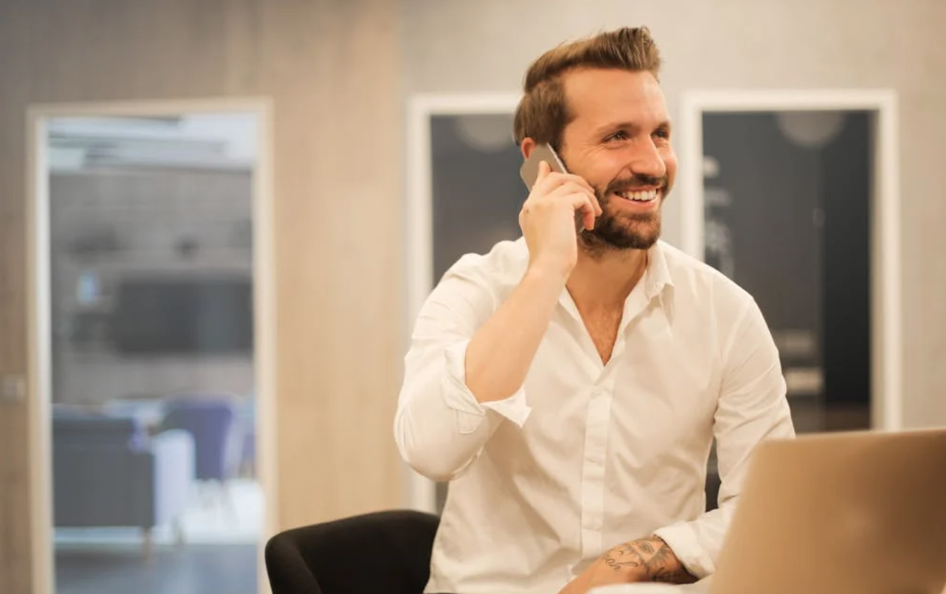 Man in white shirt smiling on phone call.