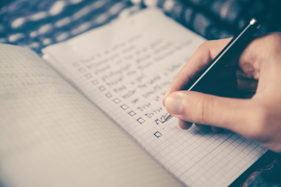 Close shot of a hand writing a checklist in a notebook