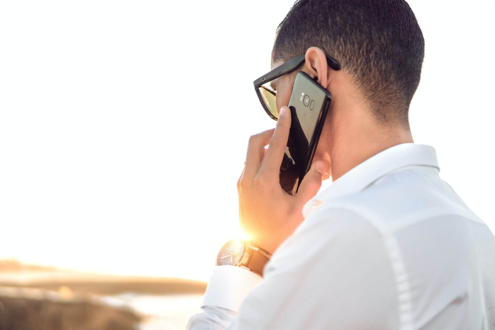 man wearing white shirt talking on the phone